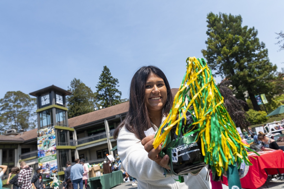 A picture of someone smiling with pom poms at the Cal Poly Humboldt Resource Fair
